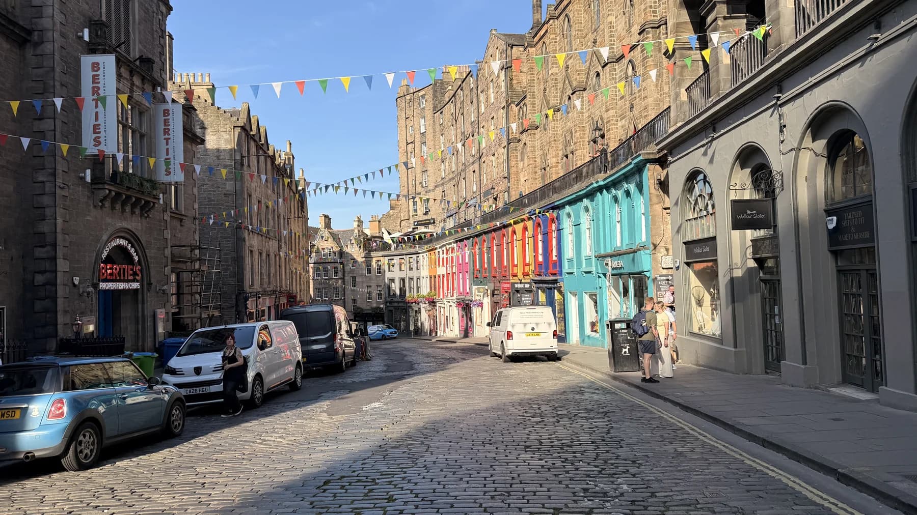 A curved street lined with colourful shopfronts and stone buildings