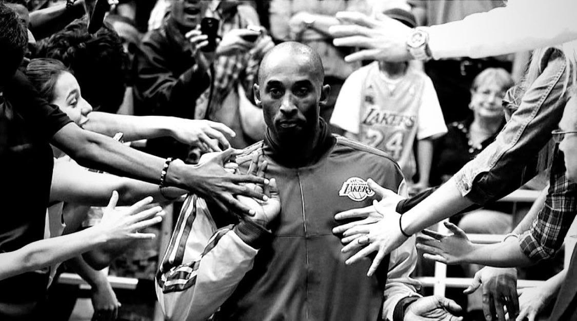 A basketball player walking between outstretched hands in a crowd.